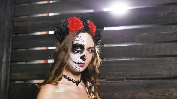 Model with Skull Makeup Poses Against Wooden Wall in Studio