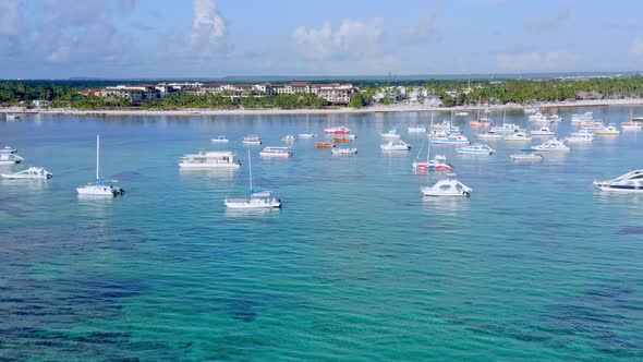 Anchored boats floating on turquoise ocean waters of Playa Bavaro in Dominican Republic. Aerial side