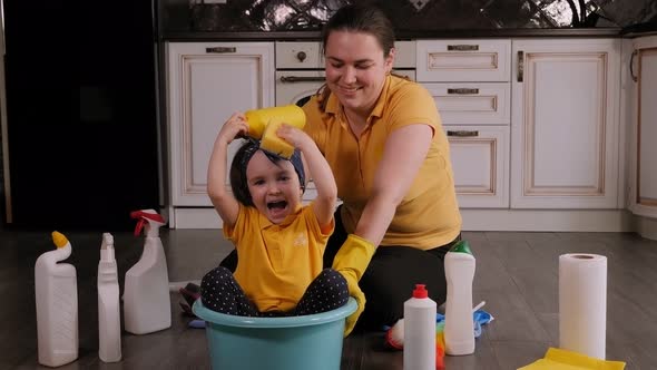 Mother and Daughter Have Fun Together Cleaning the House the Girl Sits in Basin