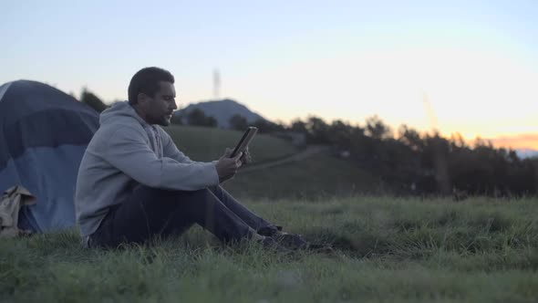 Young Man Using Tablet in Nature Mountain Outdoor at Sunrise or Sunset Dolly
