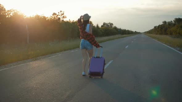 Young Woman with a Suitcase on Road. Funny Beautiful Girl Traveler. Travel Concept Video.