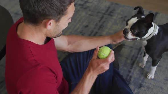 Caucasian man is playing with his dog at home