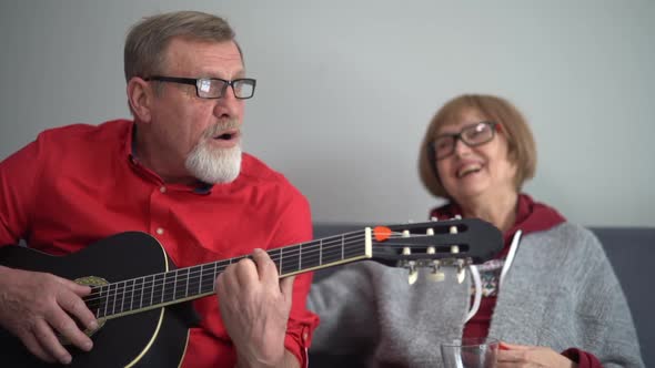 Man in a Red Shirt Plays the Acoustic Guitar and Sings for His Wife