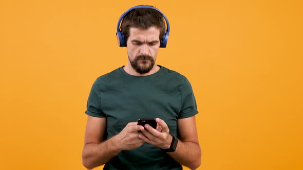 Handsome Man Puts Blue Headphones on Head, Start Listening Music and Nodding