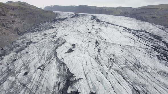 Aerial view over darkened, sooty glacier surface, in Iceland - reverse, drone shot