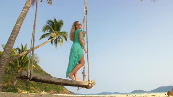 Woman Swinging on a Swing on a Tropical Beach on Shores of the Turquoise Sea