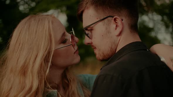 Woman Supporting Young Man Outdoors at Sunset