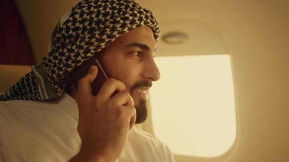 Arab Businessman Talking Cell Phone in Airplane Closeup