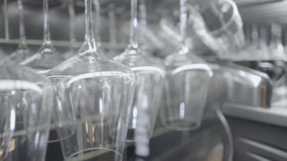 Panning Pushout of Wine Glasses Hanging By Dark Tile Wall at Bar