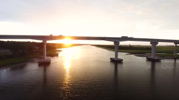 Flying towards bridge in Sunset Beach NC at sunrise while cars drive over it