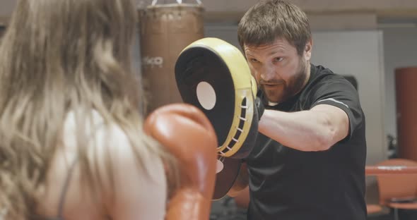 Brunette Caucasian Coach in Training Gloves Working with Female Boxer on Boxing Ring. Confident alt
