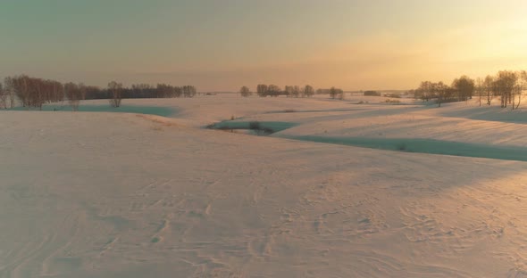 Aerial View of Cold Arctic Field Landscape Trees with Frost Snow Ice River and Sun Rays Over Horizon