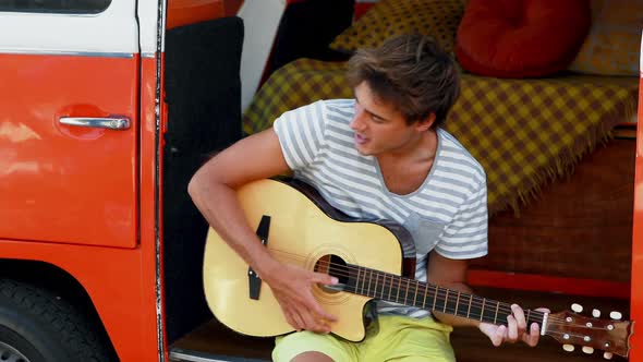 Man playing guitar in camper van 4k