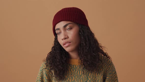 Tired African curly-haired woman looking at the camera