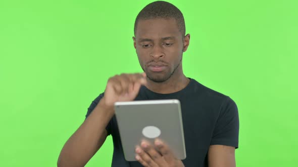 Young African Man Using Digital Tablet on Green Background