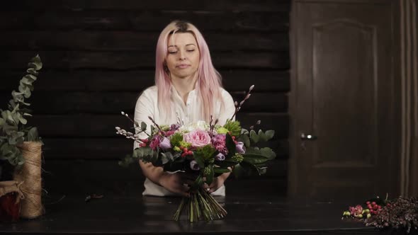 A Girl Puts on a Table a Decorated Bouquet of Flowers