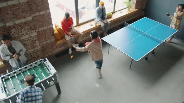 Happy Young People Relaxing During Work Break Playing Ping Pong and Foosball in Office