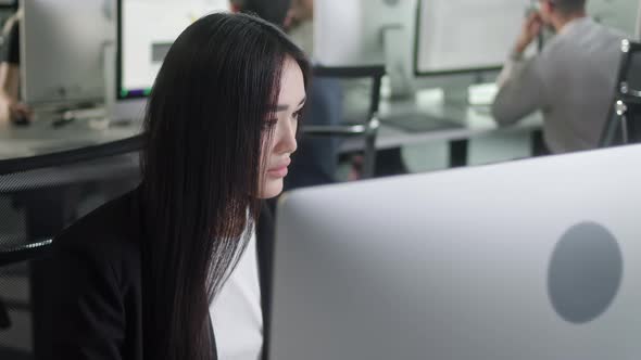 Attractive Young Woman Working on Decktop Computer While Working in Big Open Space Office