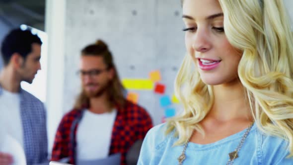 Woman using mobile phone with her colleagues in background