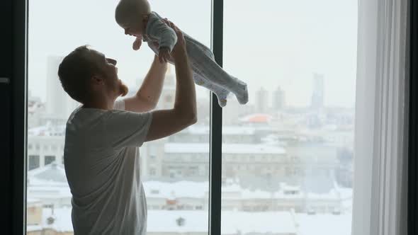 happy father picks up the baby while standing by the big window