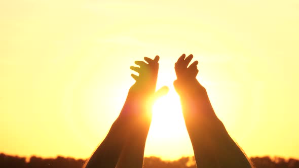 A Man and a Woman Hold Their Hands Against the Backdrop of a Beautiful Sunset, Touching and Holding