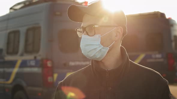 A Man in a Police Uniform is Standing Near Two Police Buses