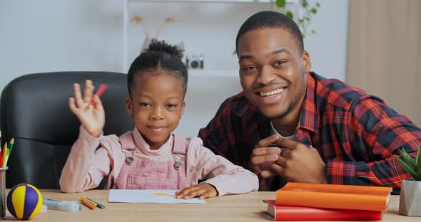 Young Father Teacher Afro American Guy with Cute Beloved Daughter Schoolgirl Sitting at Table