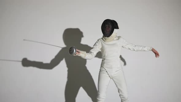 Portrait of a Young Woman Fencer Saluting with Rapier Putting on Helmet and Throwing Attacking Blows