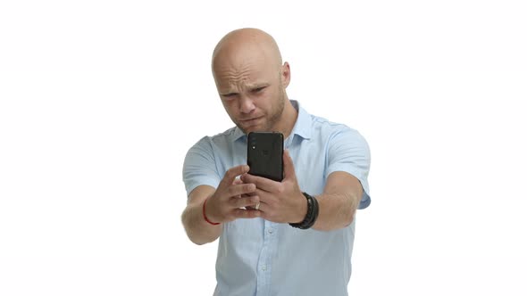 Video of Middleaged Bald Guy with Beard Looking Serious at Smartphone Trying to Take Photo Shooting