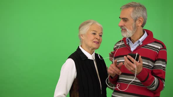 An Elderly Couple Listens To Music on a Smartphone - Green Screen Studio