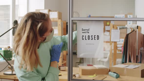 Woman in Mask Hanging Poster with Sign about Closing Store