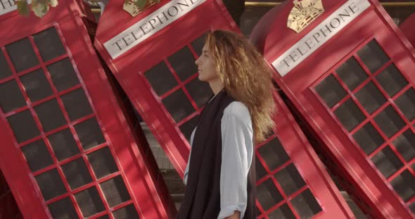 Attractive Girl Walking on a Background of Red British Phones. Travel, Tourist Places Concept