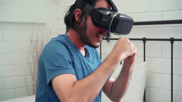 Asian man using glasses virtual reality simulator and joystick playing racing game in bedroom.