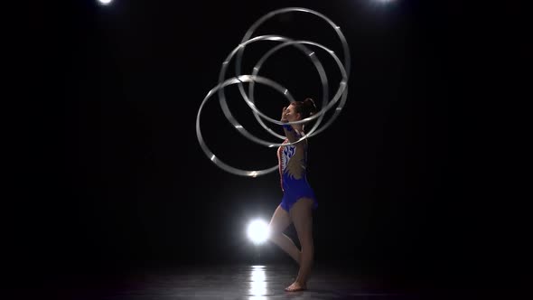 Gymnast Turns Hoops on Her Arms and Serves Up a One in a Vertical String. Side View. Black