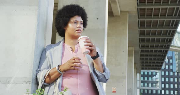 Plus size biracial woman drinking coffee in city