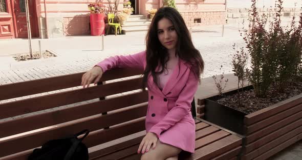 Young model in pink posing on a bench in the city