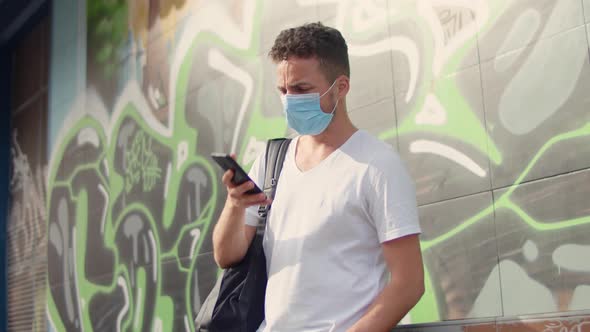 Cute Young Man in a White Tshirt and a Protective Mask in the City on a Graffiti Background