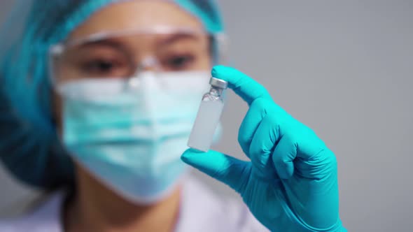 female doctor holding vaccine bottle for injection medicine