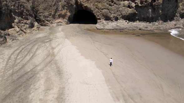 Aerial Shot Of Person Walking Towards The Cave Near Bethells Beach In New Zealand.