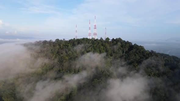 Aerial move toward four telecommunication towers at the peak of hill