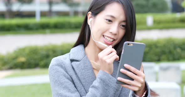 Woman talking on mobile phone with earphone at outdoor