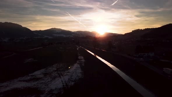 Beautiful moody winter wonderland scenery in Switzerland with a reflective river, cars and a village