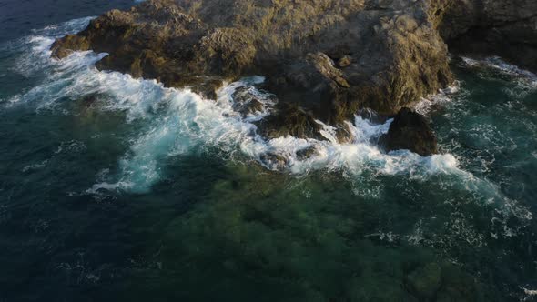 Sea waves crashing against rocks - Aerial drone view. Fly over water 