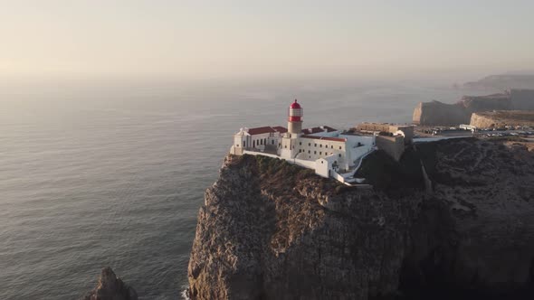 Lighthouse on the cliff, Cabo de Sao Vicente beacon and convent, Sagres, Algarve. Sunset soft light