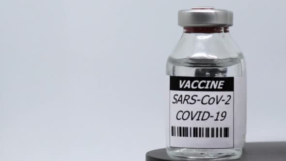 Rotating Vaccine Vials In Plain Background - Sars-Cov-2 Immunization Concept - close up, studio shot