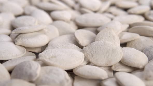 Roasted salted white pumpkin seeds. Rotation and fall in slow motion. Macro