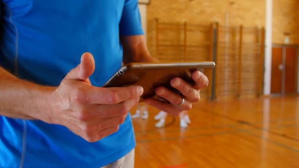 Basketball coach using digital tablet in basketball court at school 4k