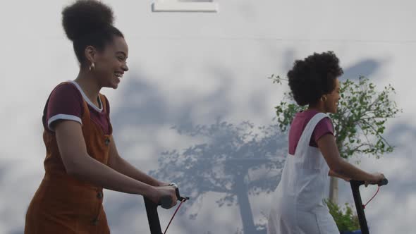 Two mixed race women riding electric scooter