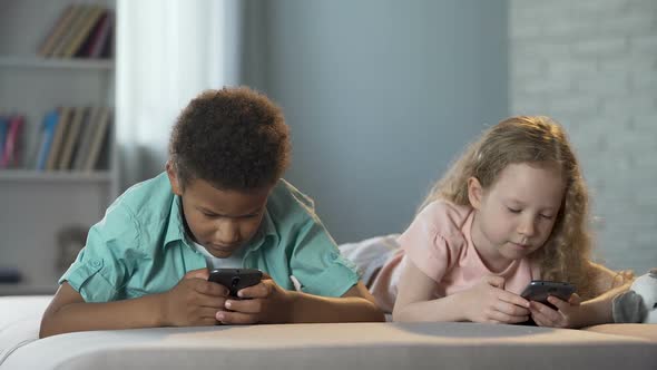 Small Children Addicted to Mobile Phones Playing Games with Concentrated Faces