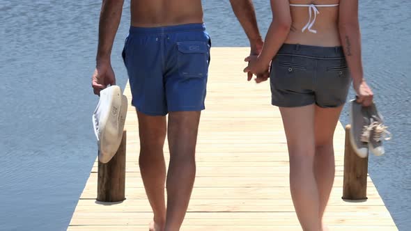 Affectionate couple walking down jetty towards lake